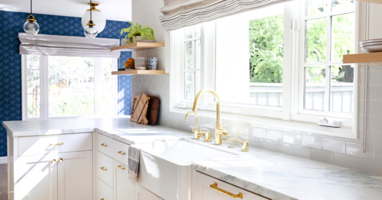 Clean kitchen with white countertops and gold faucet