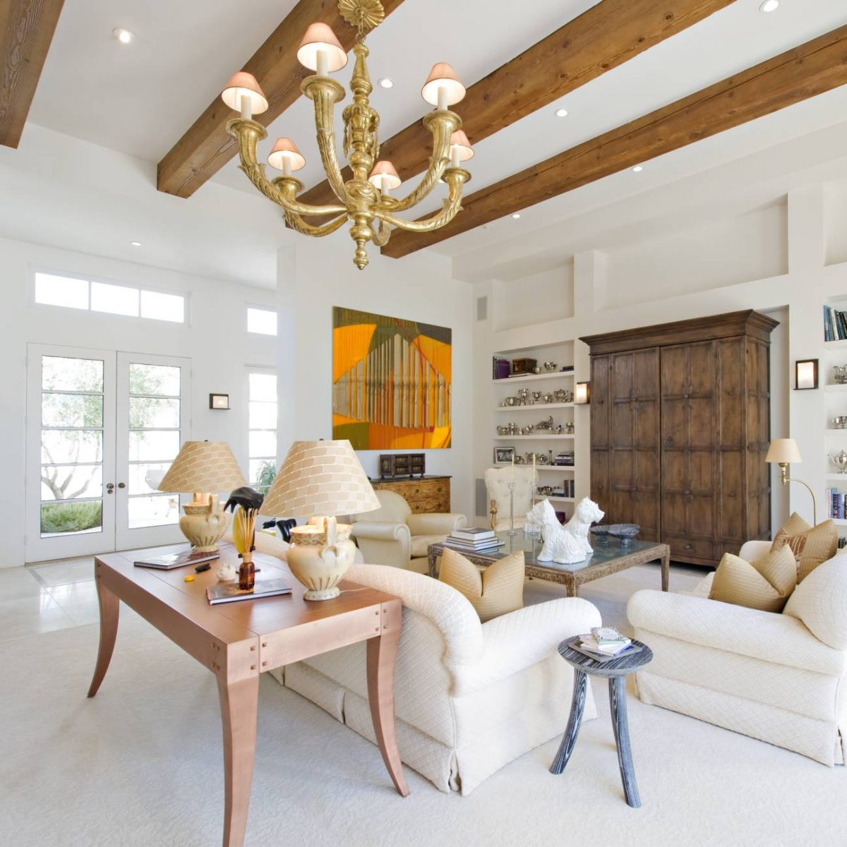large modern living room with white walls and wooden ceiling beams with a chandelier
